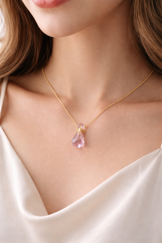 Woman wearing pink crystal perfume bottle pendant necklace on a gold chain close-up lifestyle photo