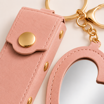 Close-up detail of the pink Lipstick Holder and Mini Heart Mirror Keychain showing stitching, texture, mirror, and gold hardware