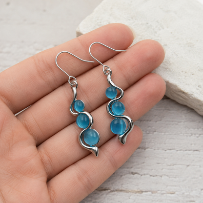 Close-up detail of the aqua-blue stones and polished silver curves on Blue Wave Dangle Earrings