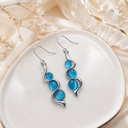 Blue Wave Dangle Earrings shown in hand for size and scale reference