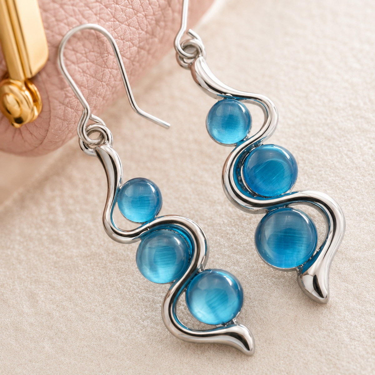 Macro detail of Blue Wave Dangle Earrings beside pink mini leather coin purse