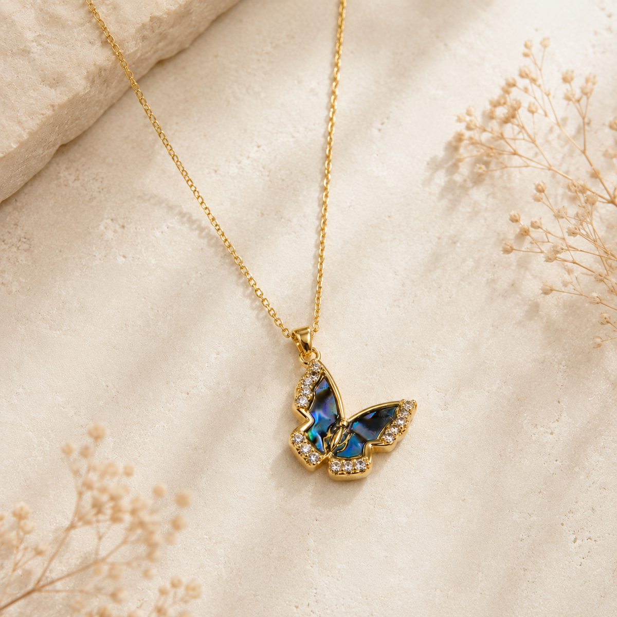 Natural Shell Butterfly Pendant Necklace displayed on a neutral stone surface with delicate florals